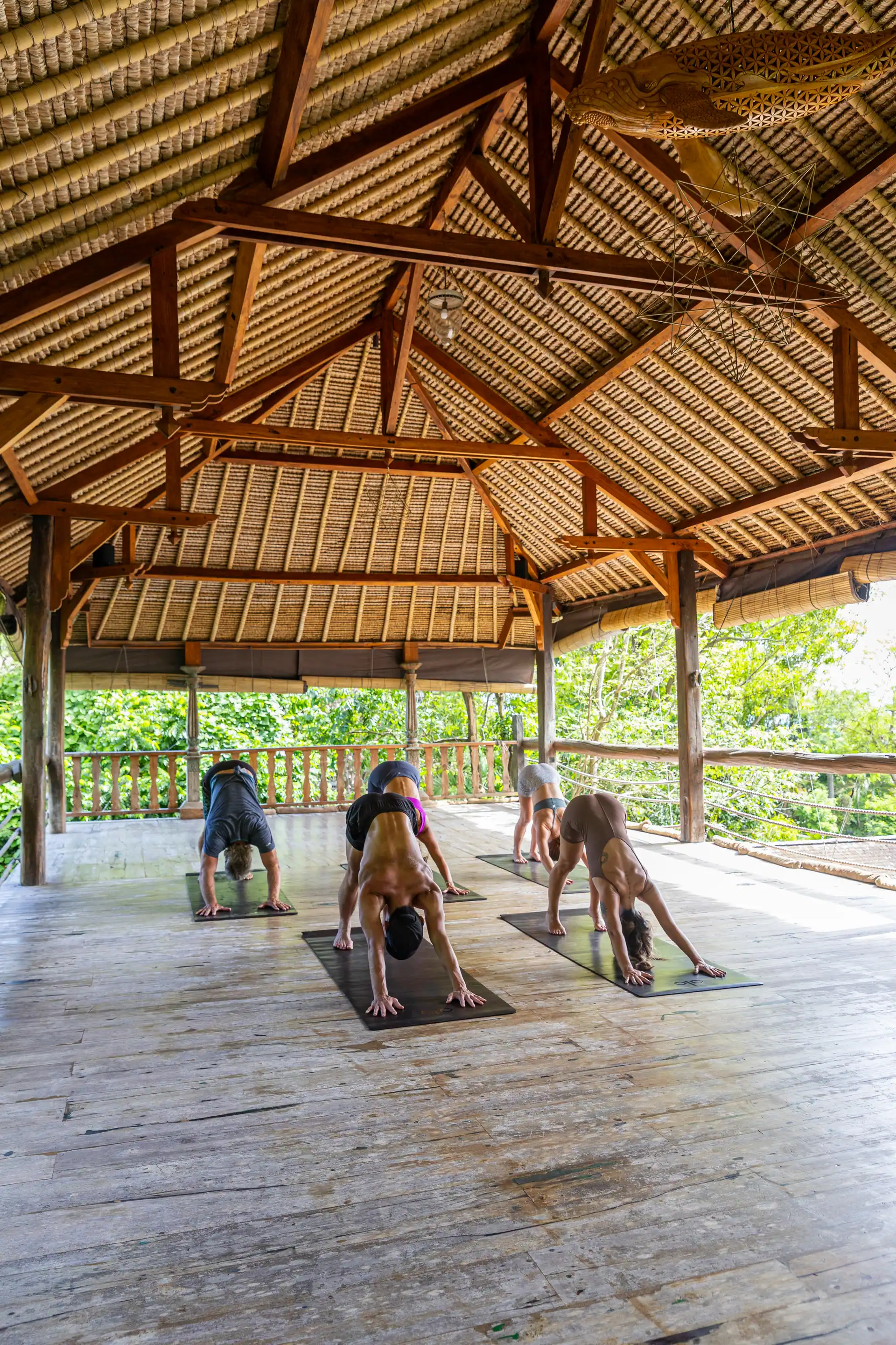 Students practicing in an open bamboo shala surrounded by jungle in Bali