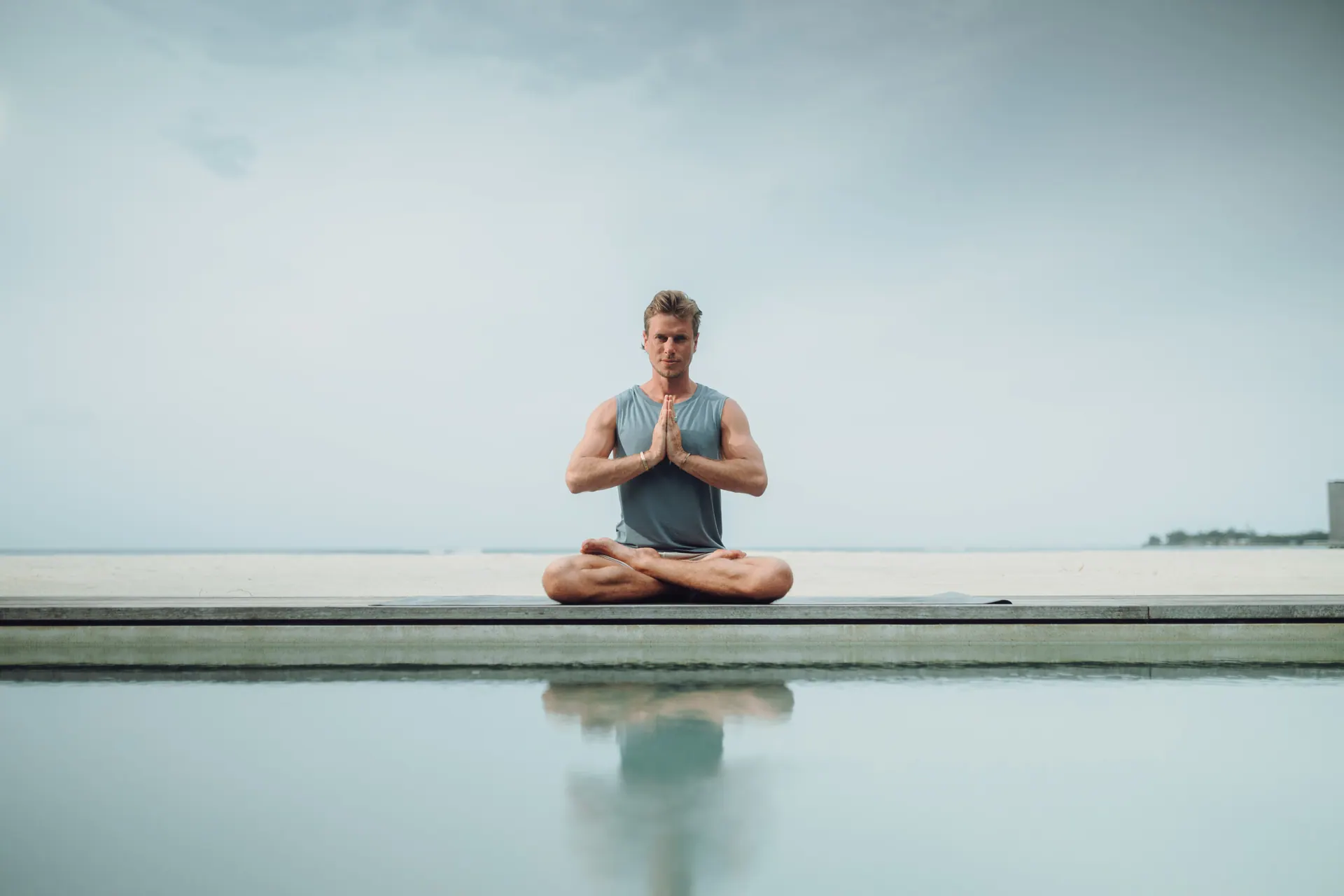 Lotus pose beside an infinity pool at first light