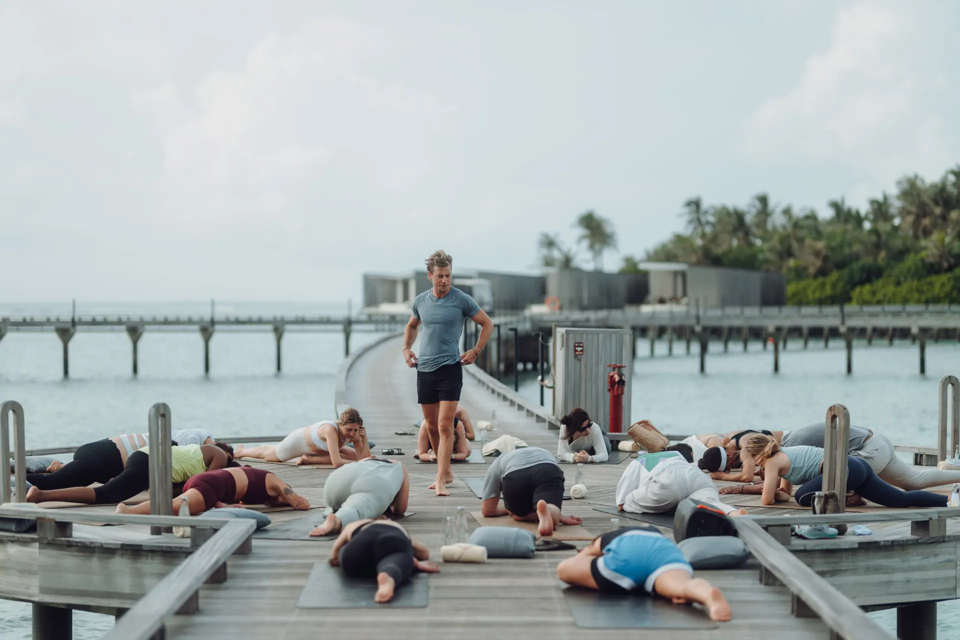 A teacher spotting a student's crow pose over the water